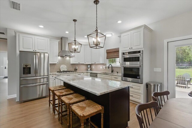 604 Judson Dr, Perry, FL 32348 - kitchen with stainless steel appliances, a sink, wall chimney exhaust hood, light wood-style floors, and a kitchen island