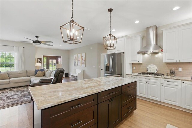 604 Judson Dr, Perry, FL 32348 - kitchen with appliances with stainless steel finishes, wall chimney exhaust hood, white cabinetry, dark brown cabinetry, and a chandelier