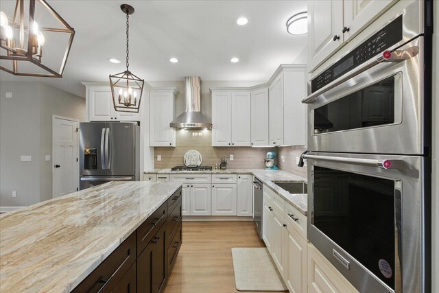 604 Judson Dr, Perry, FL 32348 - kitchen with appliances with stainless steel finishes, wall chimney range hood, a chandelier, white cabinetry, and recessed lighting