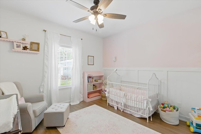 604 Judson Dr, Perry, FL 32348 - bedroom featuring wood finished floors, a nursery area, ceiling fan, and wainscoting