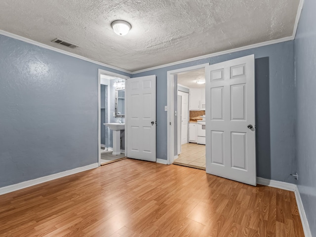 1487 Bainbridge Hwy, Quincy, FL 32352 - unfurnished bedroom with light wood-style floors, crown molding, ensuite bathroom, and a textured ceiling