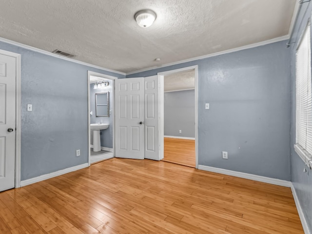 1487 Bainbridge Hwy, Quincy, FL 32352 - unfurnished bedroom featuring a textured ceiling, crown molding, light wood-style floors, and connected bathroom