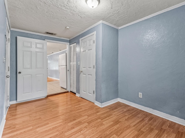 1487 Bainbridge Hwy, Quincy, FL 32352 - unfurnished bedroom featuring freestanding refrigerator, light wood-type flooring, a textured ceiling, ornamental molding, and a closet