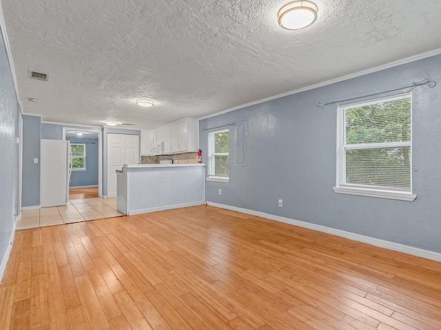 1487 Bainbridge Hwy, Quincy, FL 32352 - unfurnished living room featuring a textured ceiling, light wood-style floors, and ornamental molding