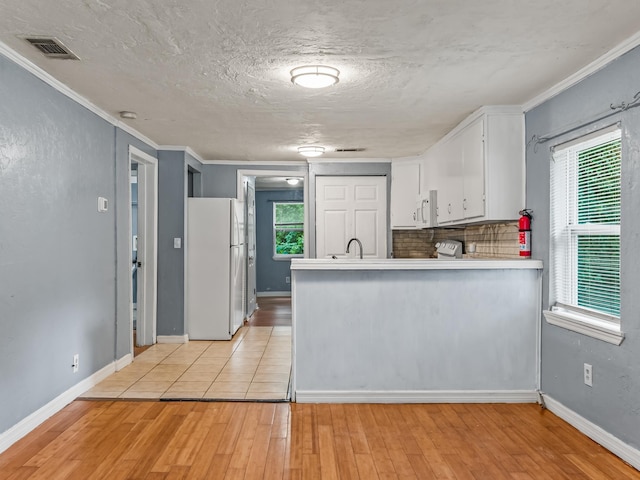 1487 Bainbridge Hwy, Quincy, FL 32352 - kitchen with freestanding refrigerator, light wood finished floors, white cabinets, a peninsula, and crown molding