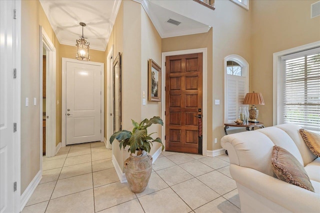 tiled foyer featuring crown molding and a chandelier