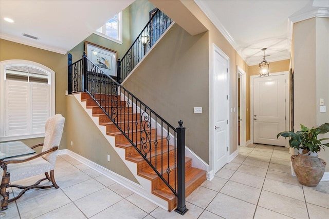 staircase featuring tile patterned flooring, ornamental molding, and a chandelier