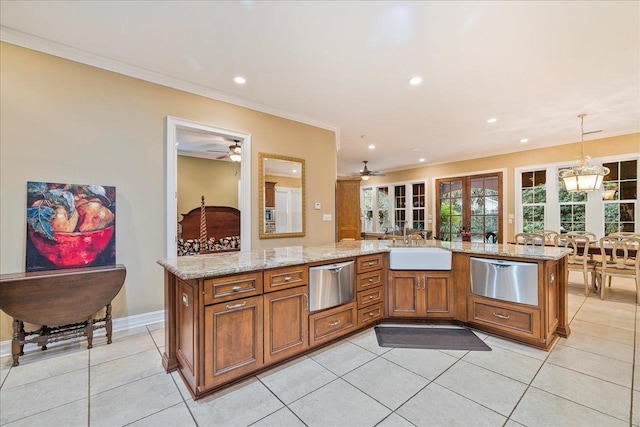 kitchen with light tile patterned flooring, decorative light fixtures, sink, light stone counters, and crown molding