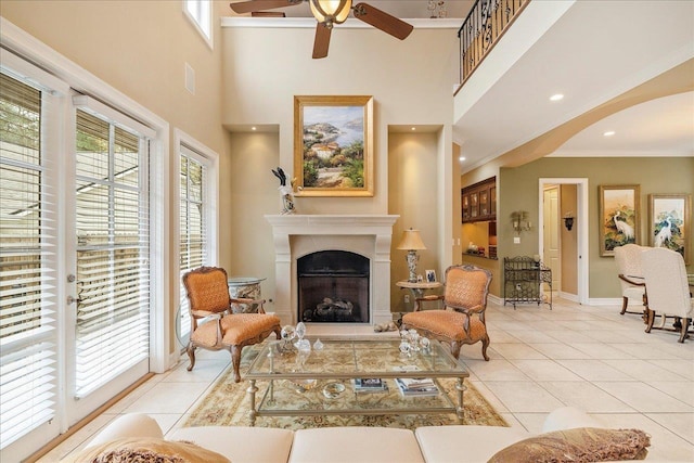 tiled living room with ornamental molding, ceiling fan, and a high ceiling