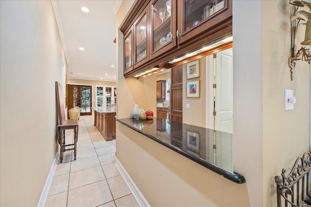 hallway featuring light tile patterned flooring and ornamental molding