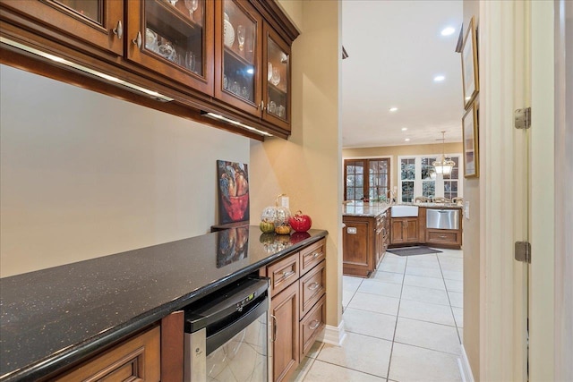 kitchen featuring sink, light tile patterned floors, decorative light fixtures, and dark stone counters