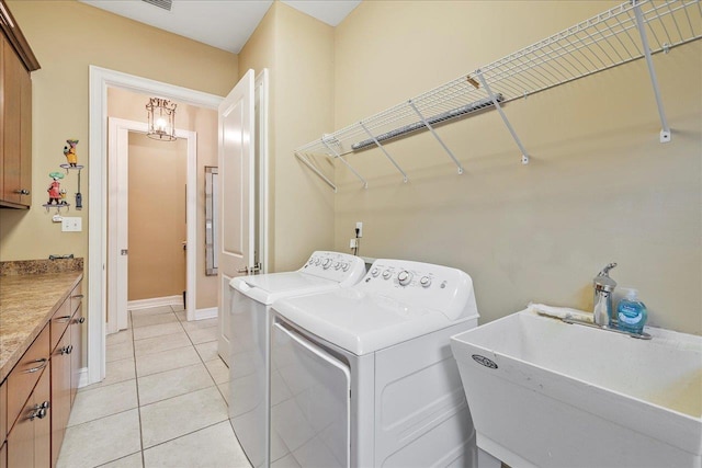 washroom with cabinets, washing machine and dryer, sink, and light tile patterned floors