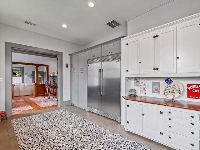 kitchen with built in refrigerator, white cabinetry, gray cabinetry, and wooden counters