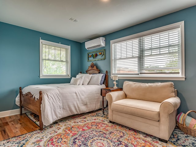 bedroom featuring light hardwood / wood-style flooring and a wall unit AC