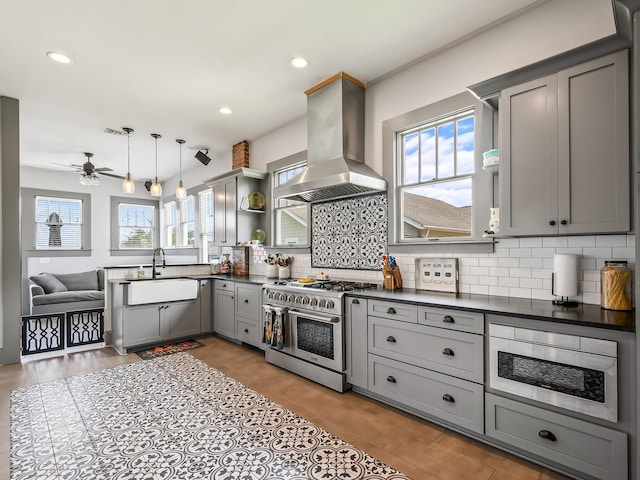 kitchen featuring sink, appliances with stainless steel finishes, gray cabinets, pendant lighting, and island exhaust hood