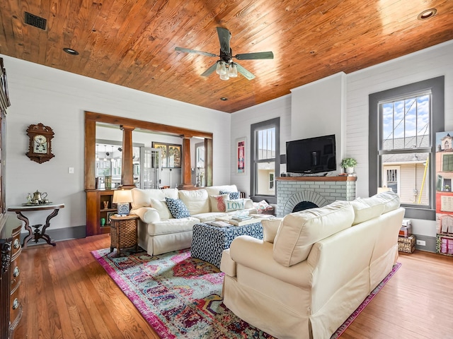 living room with ceiling fan, a brick fireplace, hardwood / wood-style floors, and wood ceiling