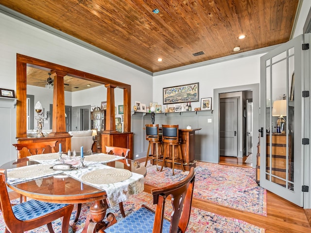 dining room with ornate columns, indoor bar, ceiling fan, wood ceiling, and light hardwood / wood-style flooring