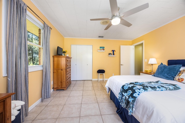 bedroom with ceiling fan, light tile patterned floors, a closet, and crown molding