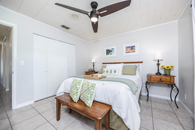 bedroom featuring ceiling fan, light tile patterned floors, a closet, and ornamental molding