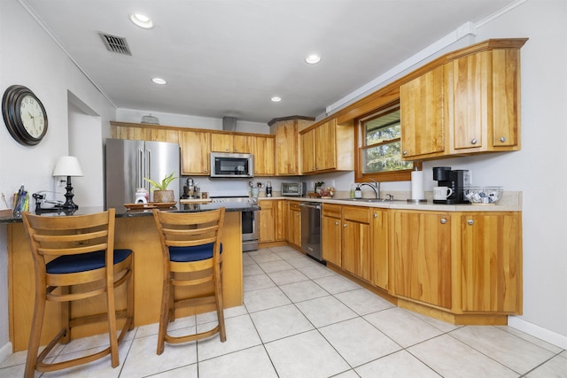 kitchen featuring light tile patterned flooring, sink, a breakfast bar area, stainless steel appliances, and ornamental molding