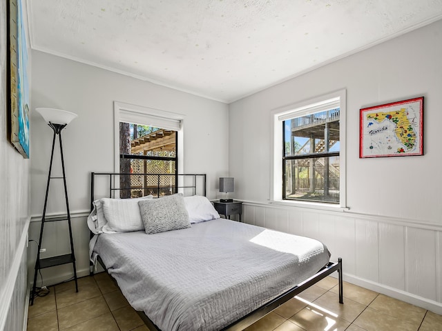 bedroom with multiple windows, crown molding, and light tile patterned floors