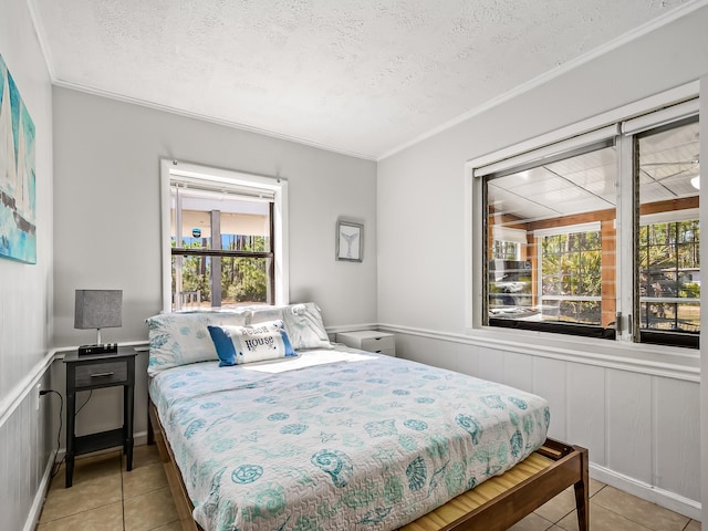 bedroom featuring light tile patterned flooring, ornamental molding, and a textured ceiling