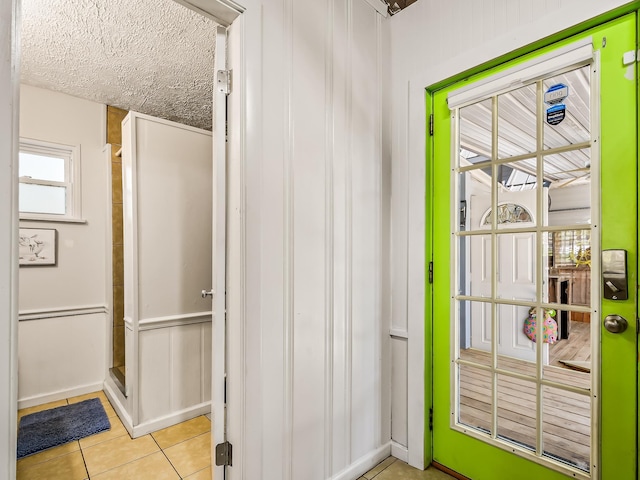 doorway with light tile patterned floors and a textured ceiling