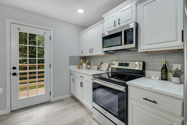 kitchen with stainless steel appliances, decorative backsplash, white cabinetry, and light stone countertops