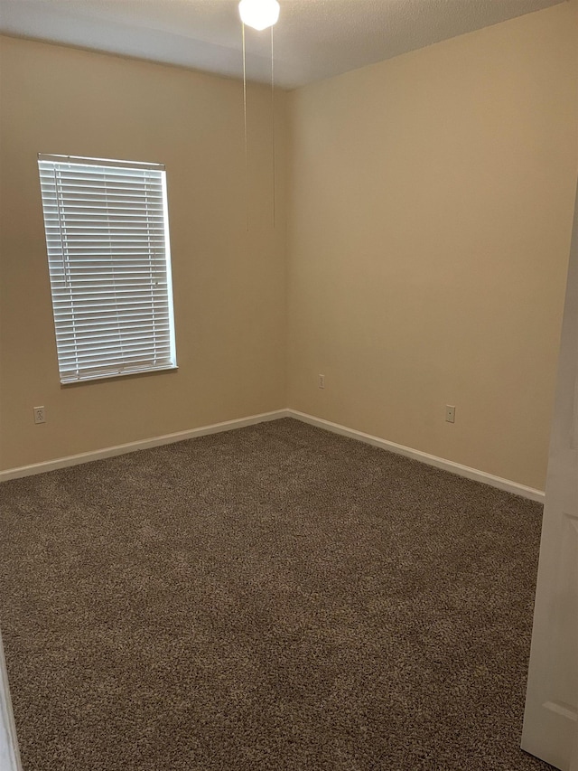 unfurnished room featuring dark carpet