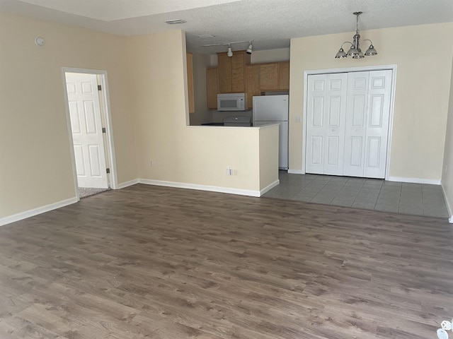 unfurnished living room with a textured ceiling, dark hardwood / wood-style floors, and a notable chandelier