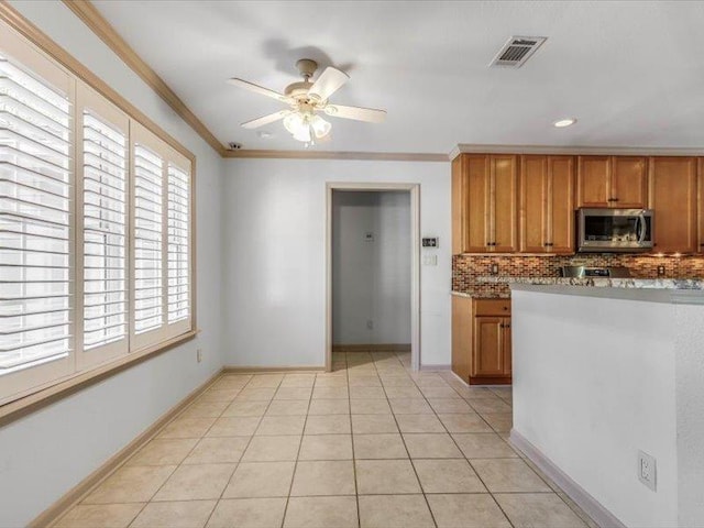 kitchen with light tile patterned floors, light stone countertops, ceiling fan, decorative backsplash, and ornamental molding