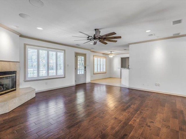 unfurnished living room with a fireplace, ceiling fan, crown molding, and dark hardwood / wood-style flooring