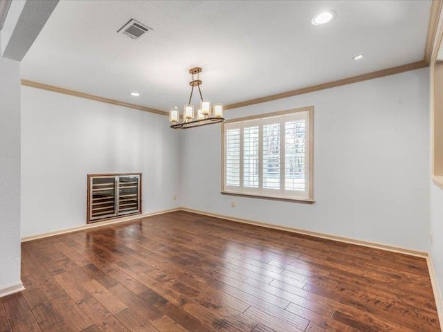 unfurnished room featuring ornamental molding, dark wood-type flooring, and a notable chandelier