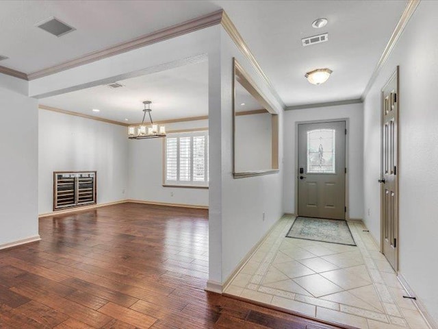 foyer featuring a chandelier, crown molding, and hardwood / wood-style floors