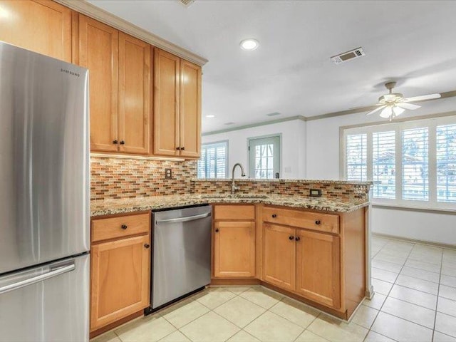 kitchen with stainless steel appliances, light stone counters, backsplash, light tile patterned floors, and kitchen peninsula