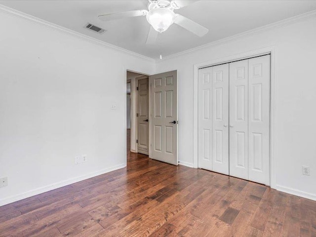 unfurnished bedroom with ceiling fan, a closet, dark wood-type flooring, and ornamental molding