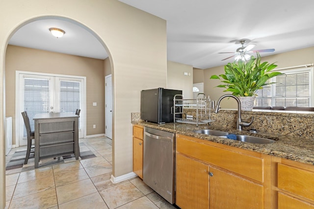 kitchen featuring stone countertops, a healthy amount of sunlight, sink, and dishwasher