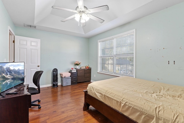 bedroom featuring a raised ceiling, ceiling fan, and dark hardwood / wood-style floors