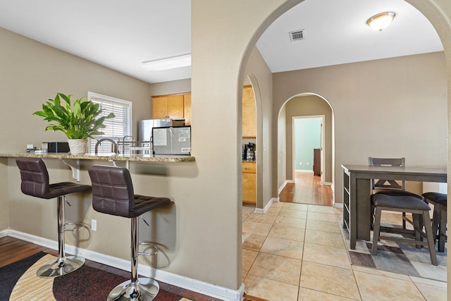 kitchen featuring light wood-type flooring, light brown cabinetry, and light stone countertops