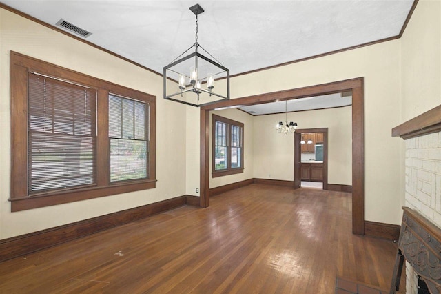 interior space with a notable chandelier, dark wood finished floors, baseboards, visible vents, and ornamental molding