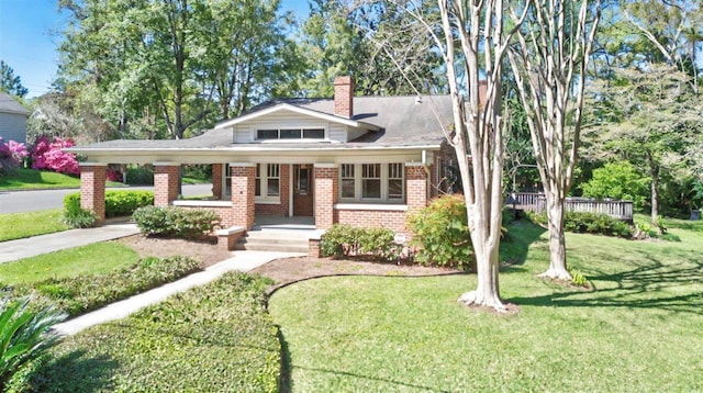 view of front of property with driveway, a front yard, an attached carport, a chimney, and brick siding