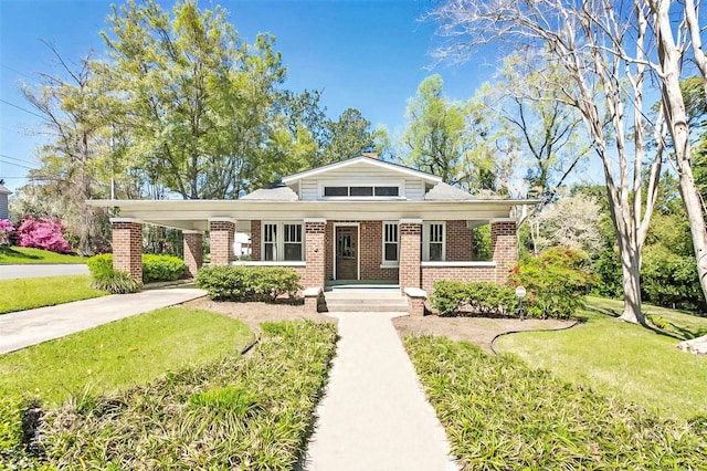 view of front of home featuring brick siding, an attached carport, driveway, and a front lawn