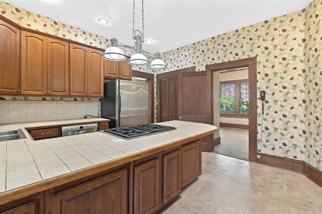 kitchen featuring wallpapered walls, stainless steel appliances, and tile countertops