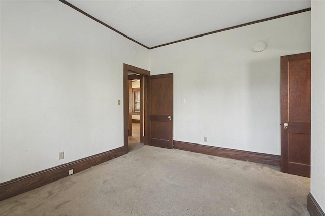 unfurnished room with ornamental molding, carpet, and baseboards