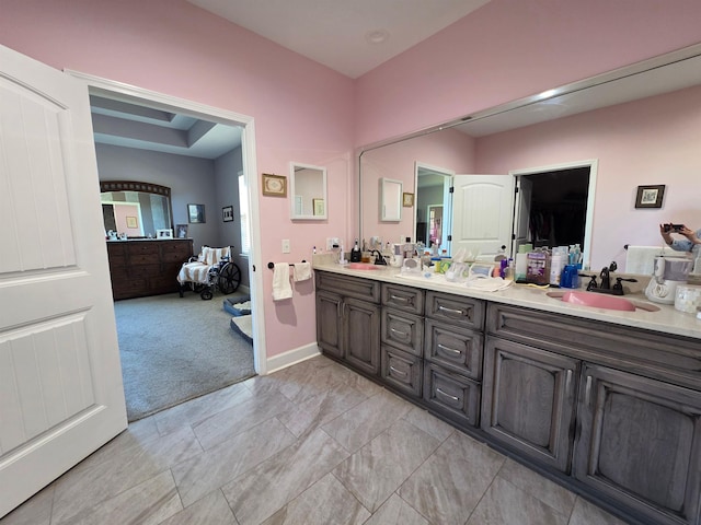 full bath with double vanity, baseboards, and a sink