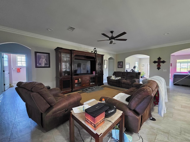 living area featuring arched walkways, visible vents, crown molding, and baseboards