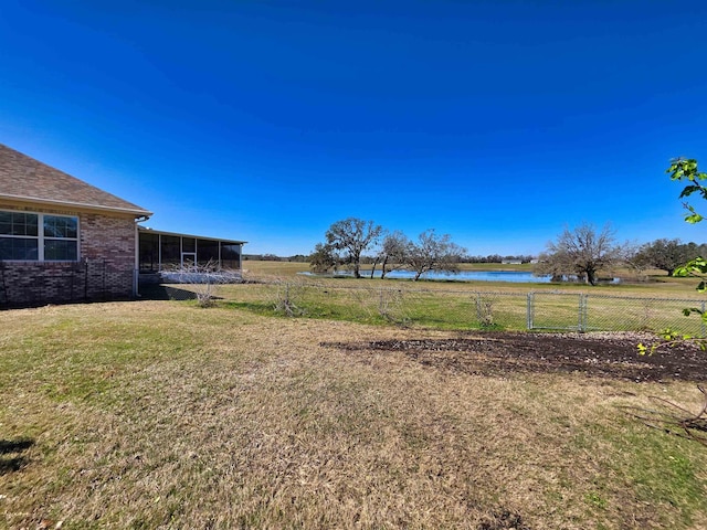 view of yard with a sunroom, a water view, and fence