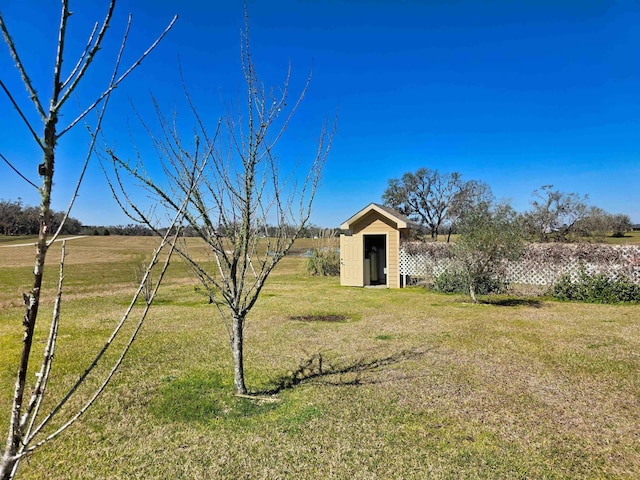 view of yard featuring an outbuilding, a rural view, and a shed