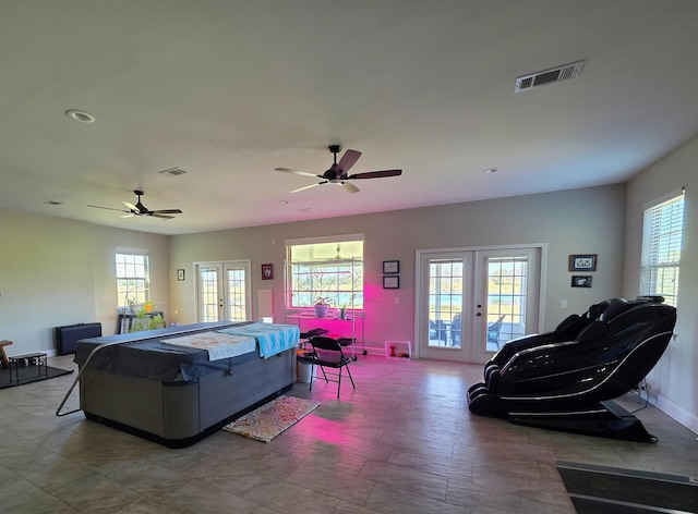 living area featuring baseboards, visible vents, a ceiling fan, and french doors