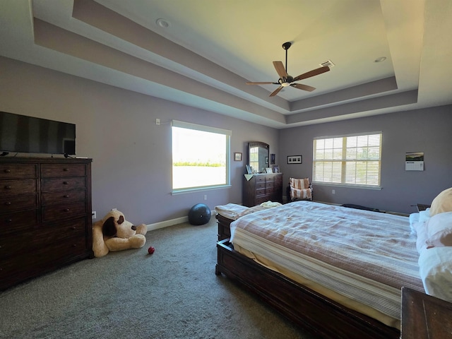 carpeted bedroom featuring a raised ceiling, multiple windows, visible vents, and baseboards